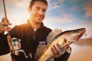 釣り竿で魚を持ち上げるフランスの男性。