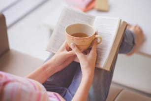 フランスで本とお茶を持つ女性。