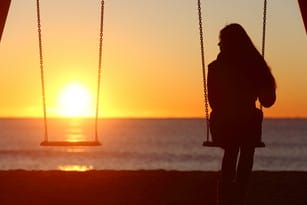 フランスの夕暮れ時にブランコに座る女性。