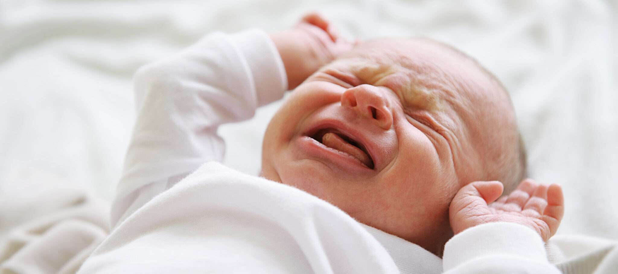 フランスの白いベッドで赤ちゃんが泣いている。 フランスの白いベッドで赤ちゃんが泣いている。