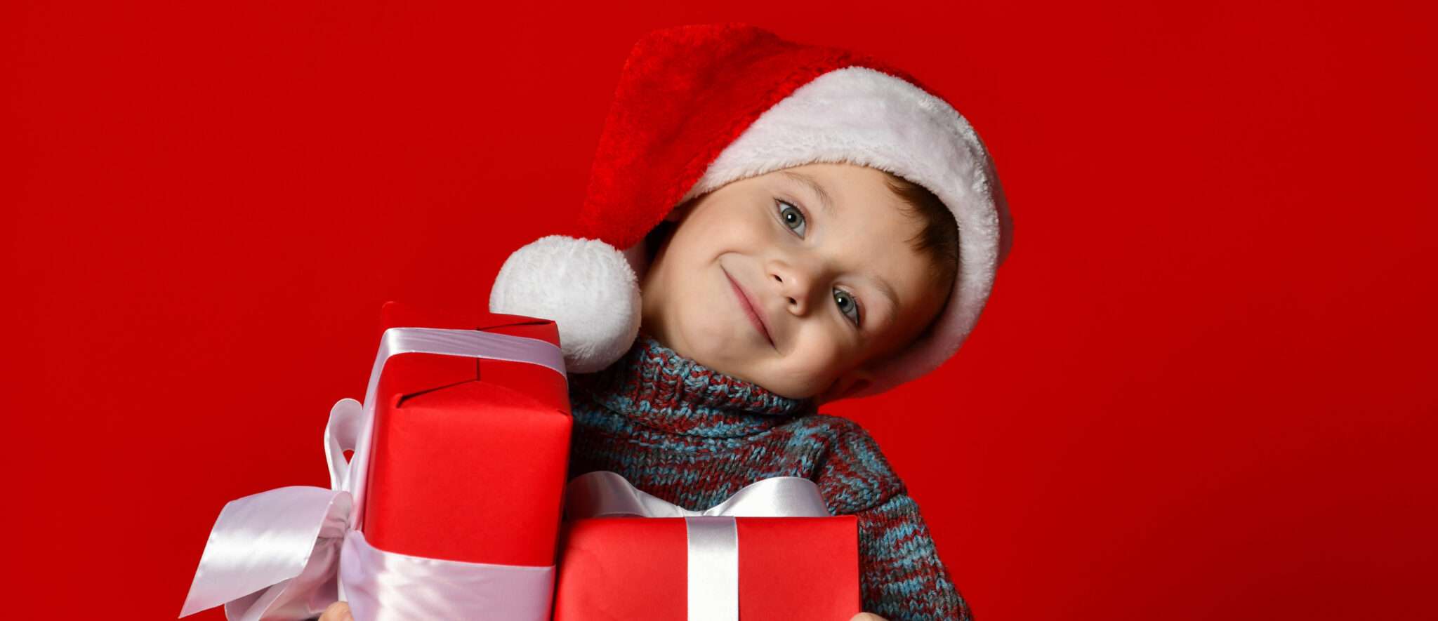 フランスのインスピレーションを感じさせる赤い背景にプレゼントを持ったサンタ帽子をかぶった少年。