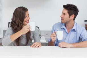 キッチンのテーブルに座ってコーヒーを飲むフランス人の男性と女性。