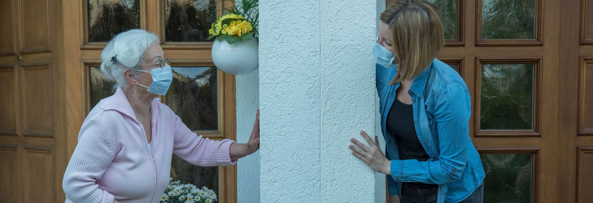 フランス（フランス）で、フェイスマスクをした女性が年配の女性と話している。