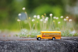 Unbus scolaire jouet se trouve sur une surface en beton。