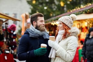 フランスのクリスマスマーケットでコーヒーを飲むカップル。