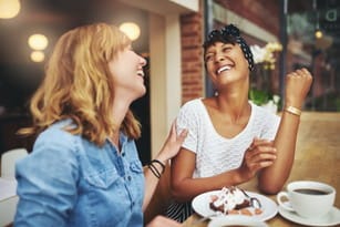 フランスのカフェのテーブルで笑っている 2 人の女性。