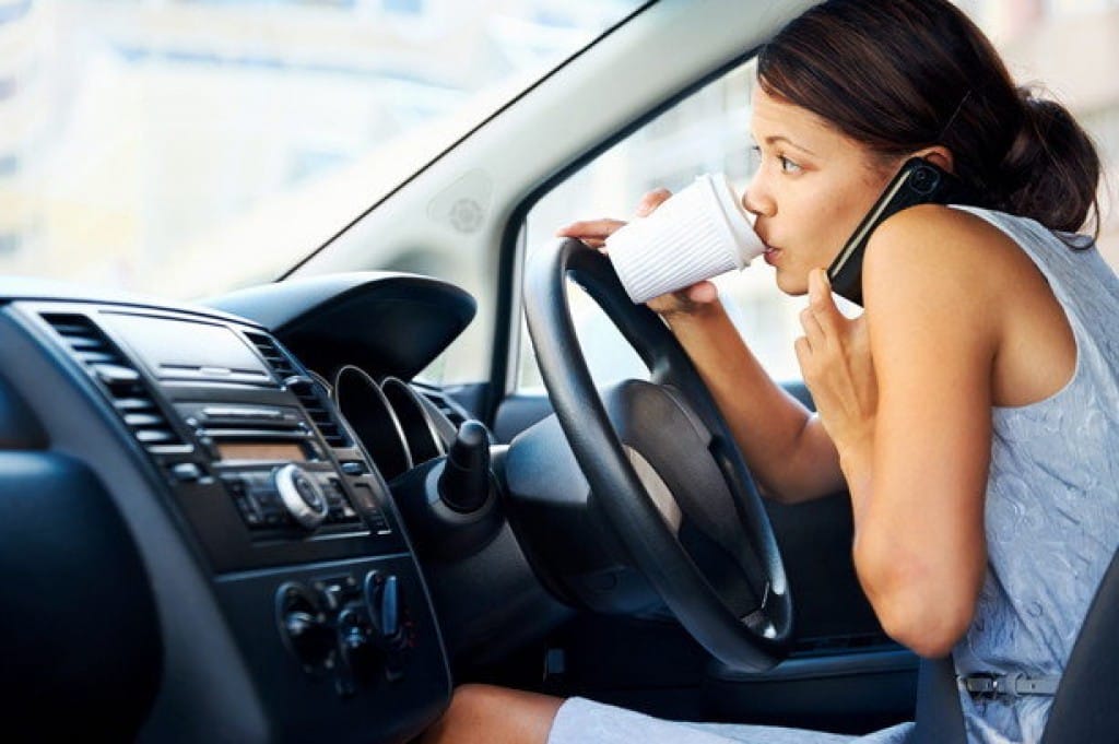 フランスで車の中でコーヒーを飲みながら電話をする女性。