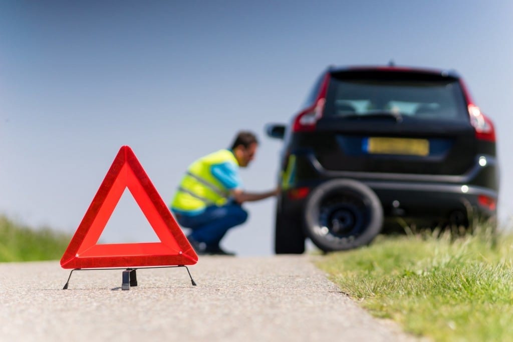 フランスの道路脇でタイヤを修理する男性。