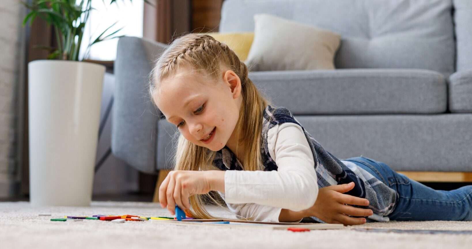 フランスで床に寝そべって積み木で遊ぶ少女。