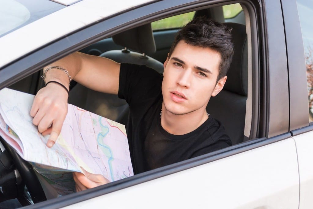 車の中でフランスの地図を見ている若い男性。