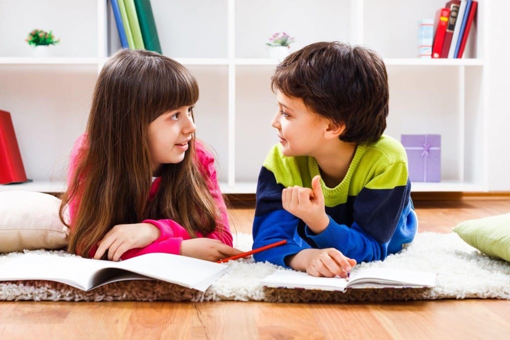 床に横たわり、一緒に本を読んでいる 2 人の子供。