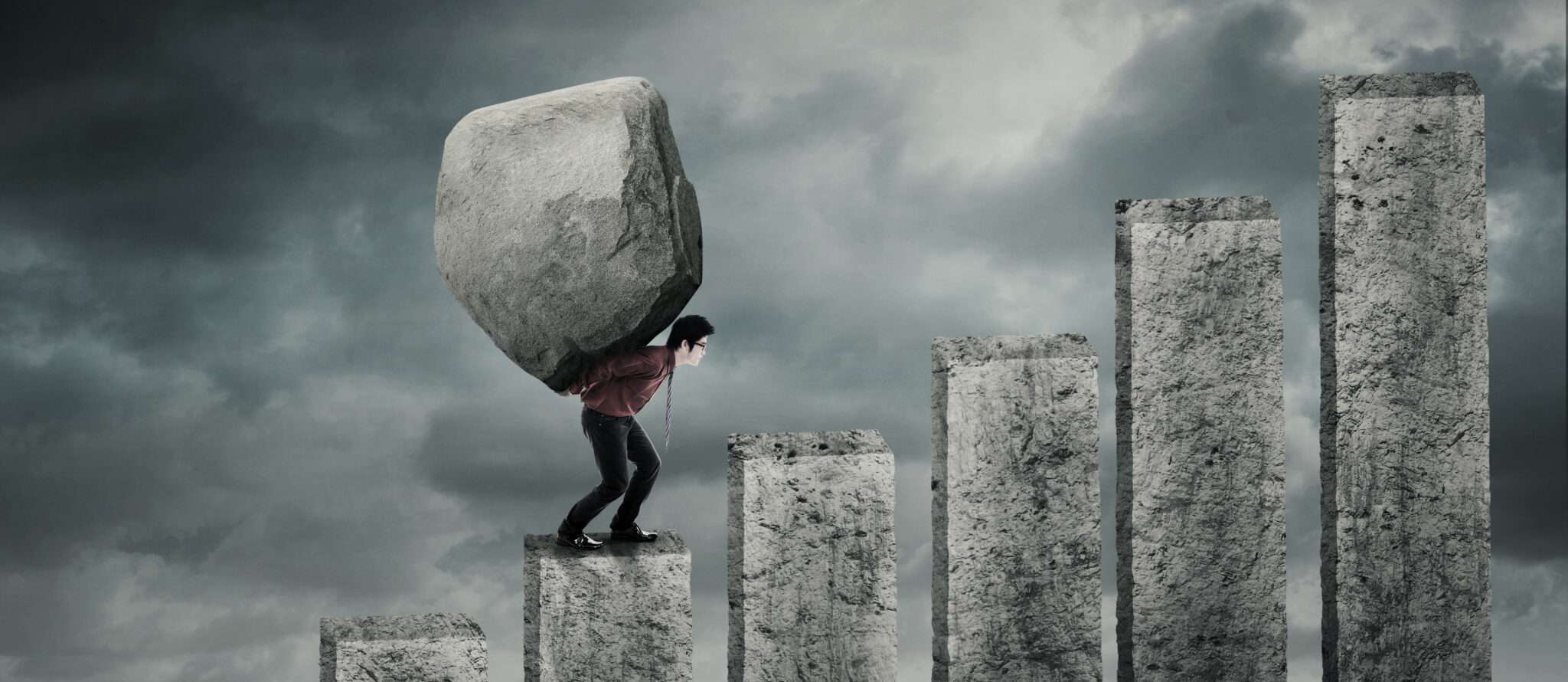 フランスで大きな石を抱えて階段を上るビジネスマン。