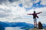 フランスで山の頂上に腕を広げて立つ女性。