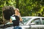 フランスでボンネットを開けたまま車の横に立つ男性。