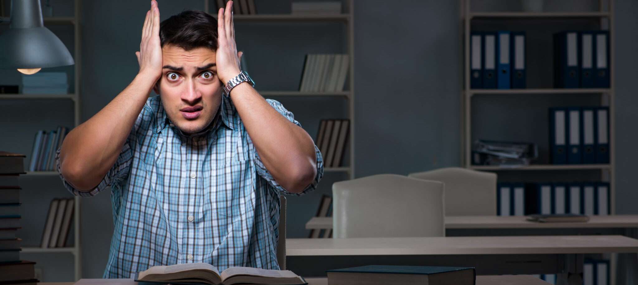 本の前で頭に手を当て、フランスの謎について熟考する男性。