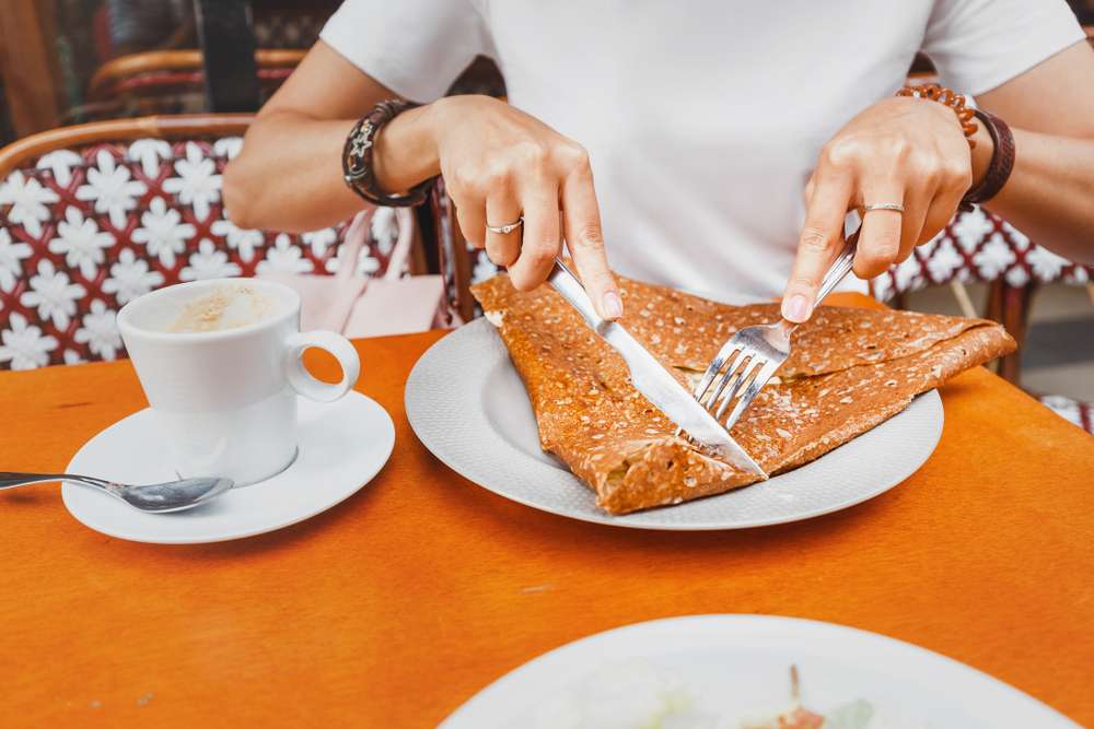 フランスのレストランでおいしいクレープを楽しむ女性。