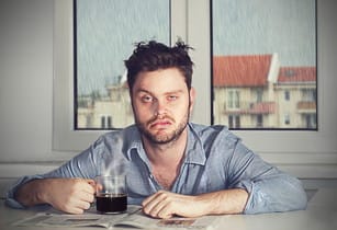 フランスでコーヒーを飲みながらテーブルに座る男性。