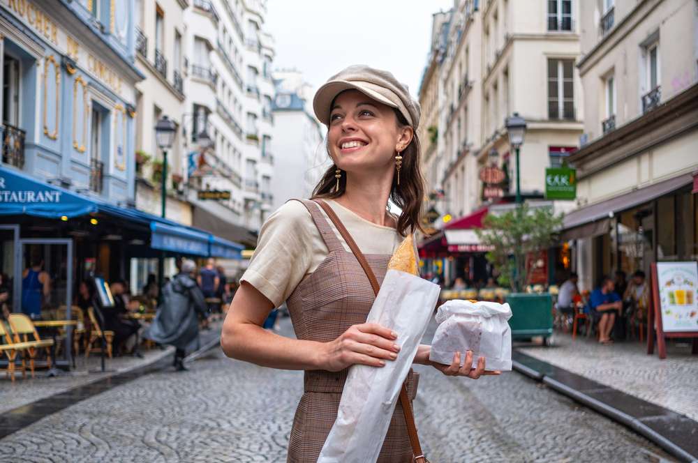 帽子をかぶった女性がフランスのパリの通りを歩いています。