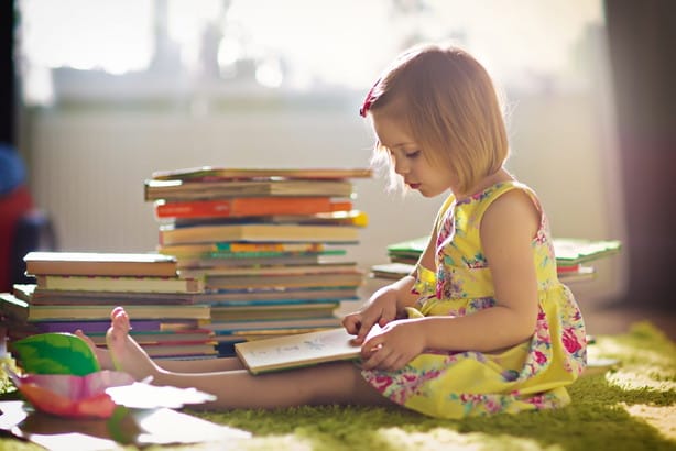 フランスで小さな女の子が床に座って本を読んでいます。