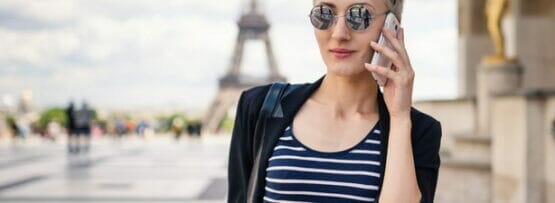 フランスのエッフェル塔の前で女性が携帯電話で話している。