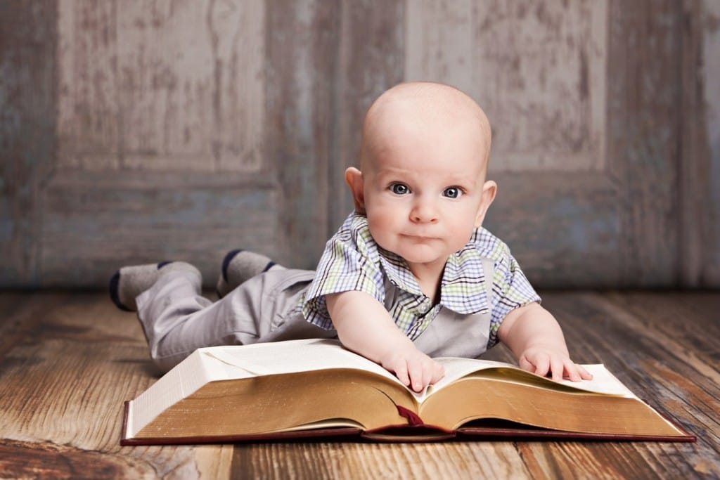 木の床に寝そべってフランスに関する本を読んでいる赤ちゃん。