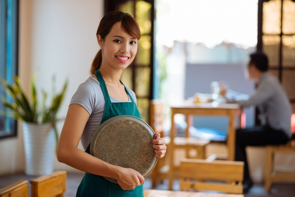 日本食レストランで皿を持つアジア人のウェイトレス。