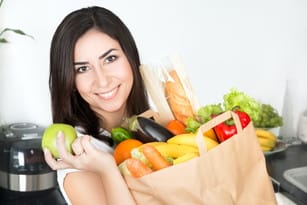 フランスで買った野菜や果物が入った紙袋を持った女性。