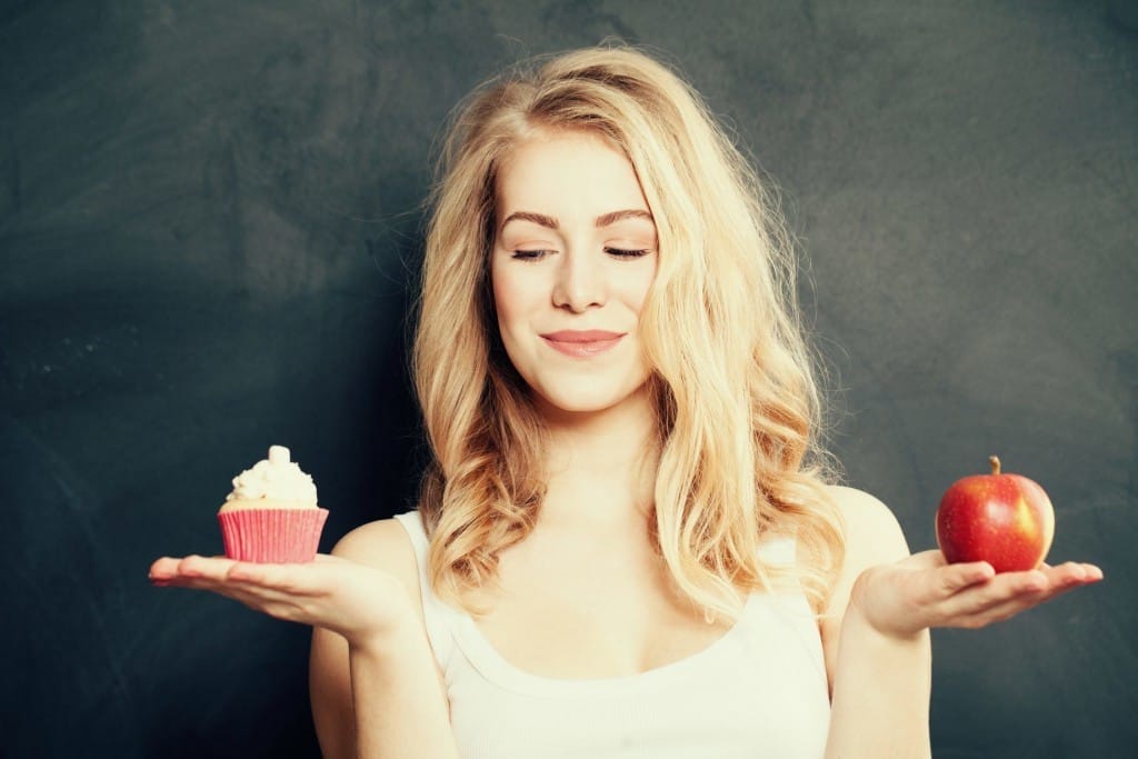 フランスの黒板の前でリンゴとカップケーキを持つ女性。