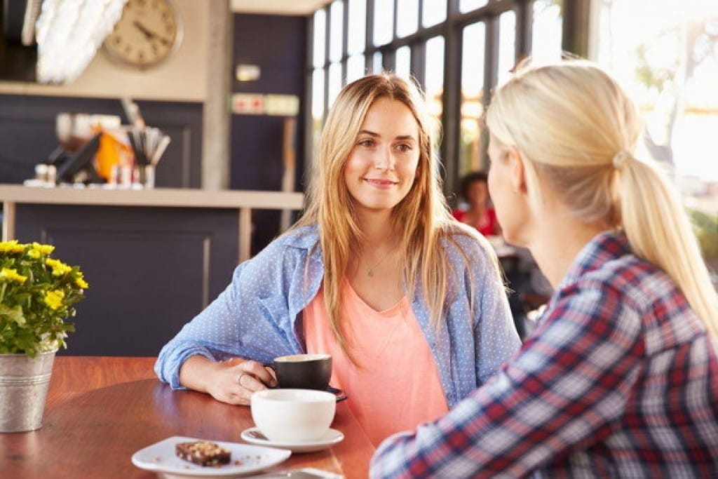 フランスのカフェのテーブルで話している 2 人の女性。