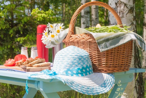 フランスから来た、食べ物の入ったバスケットと帽子を備えたピクニックテーブル。 フランスから来た、食べ物の入ったバスケットと帽子を備えたピクニックテーブル。