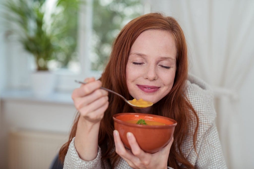 フランスから来た赤毛の女性がボウルに入ったスープを食べている。