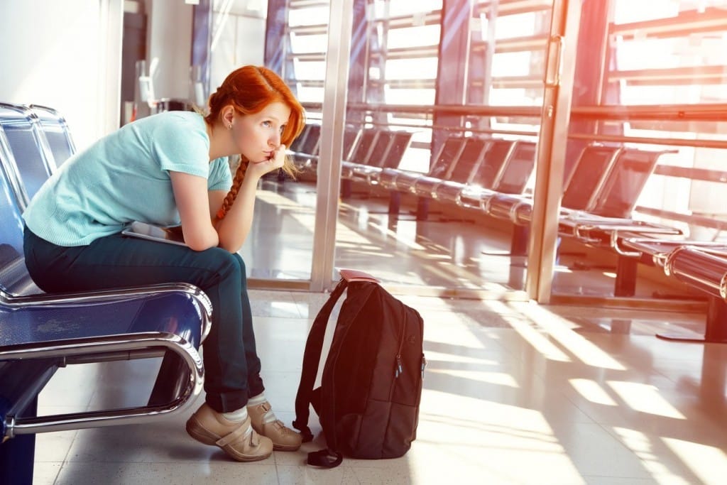 フランスの空港のベンチに座っている若い女性。