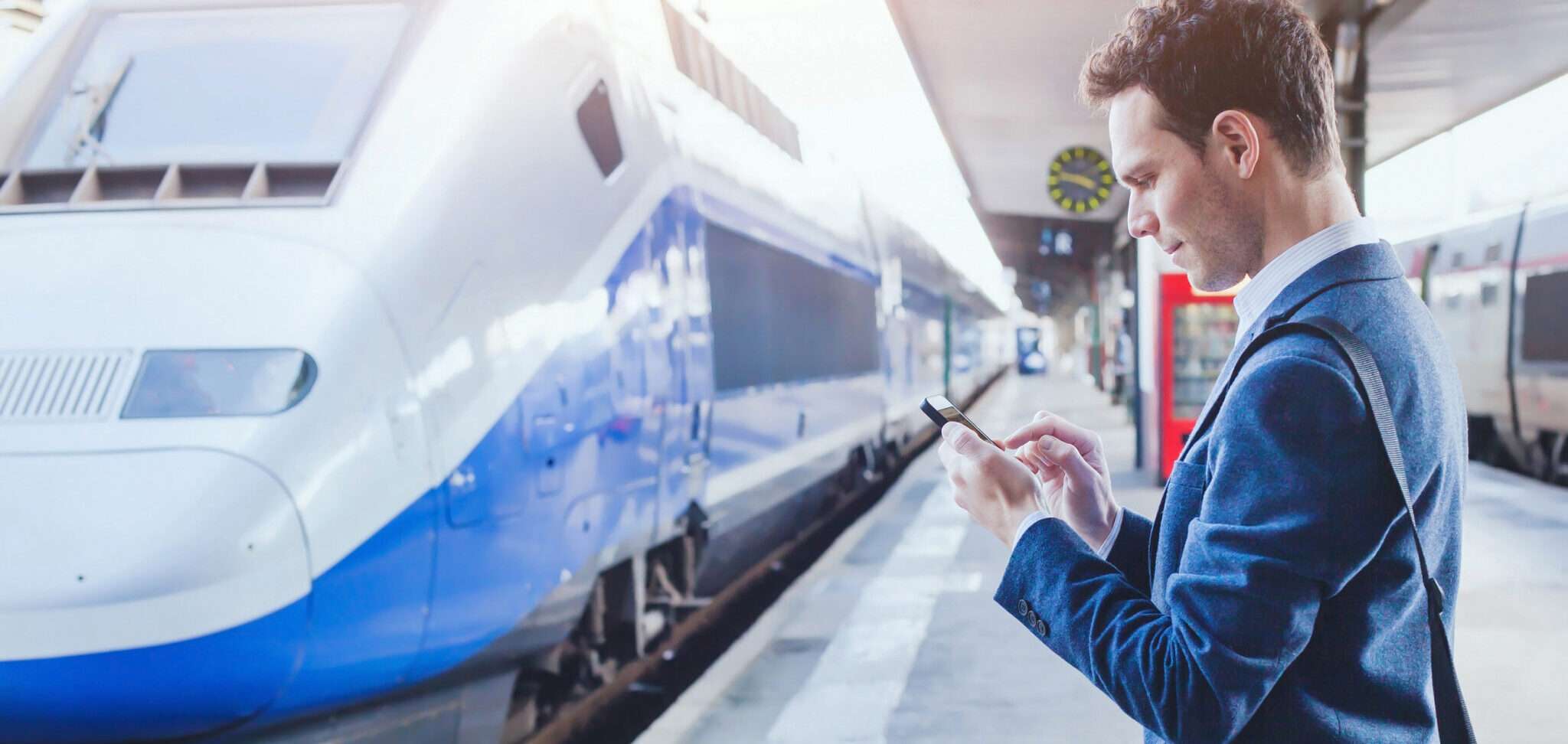 フランスの電車の横に立つスーツを着た男性。