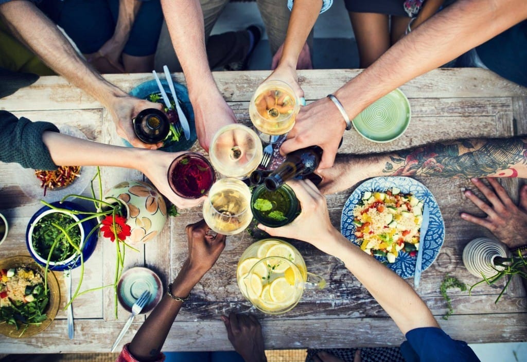 食べ物でいっぱいのテーブルの周りで手をつないでいるフランスからの人々のグループ。