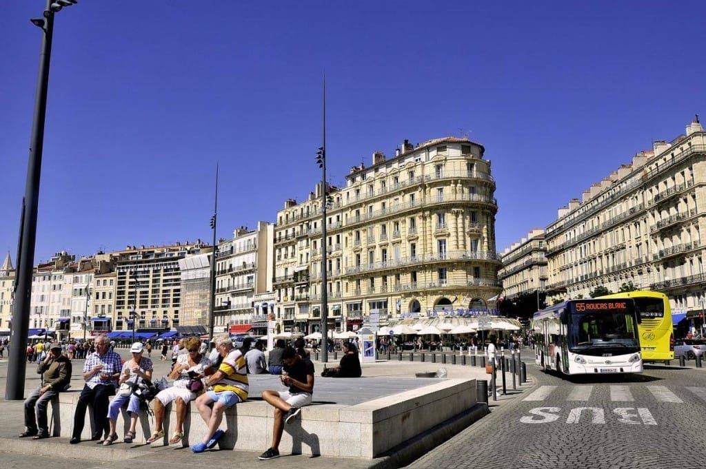 フランスの建物の前のベンチに座っている人々のグループ。