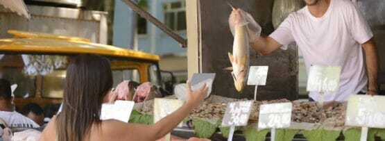 フランスの屋外市場で女性に魚を売る男性。