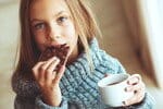 フランス - 趣のあるフランスのカフェでコーヒーを優雅に持ちながらチョコレートを味わう若い女の子。