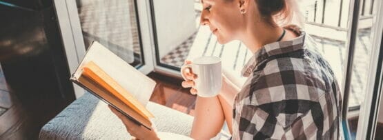 女性がソファに座ってフランスに関する本を読んでいます。