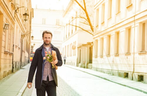 フランスの通りを男性が花束を持って歩いている。