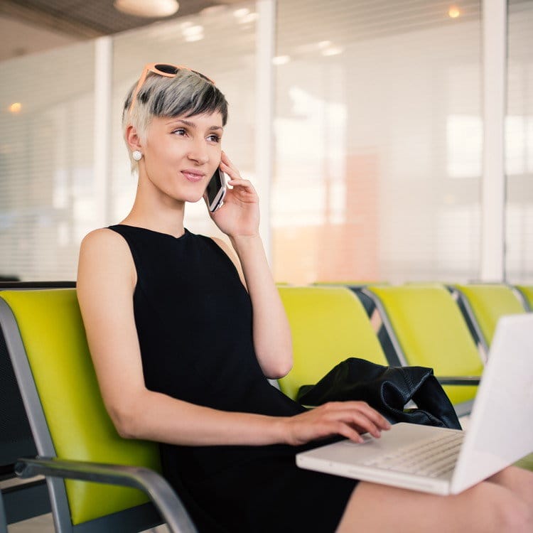 フランスでラップトップを膝の上に置き、緑の椅子に座る女性。