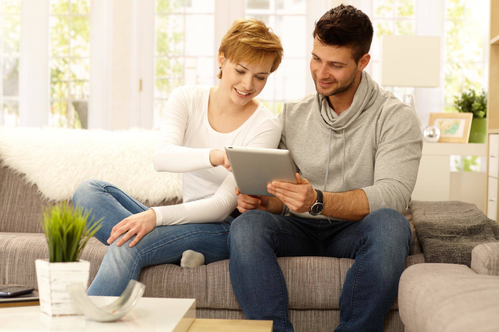 ソファに座ってタブレット コンピューターを見ているフランスの男性と女性。 ソファに座ってタブレット コンピューターを見ているフランスの男性と女性。