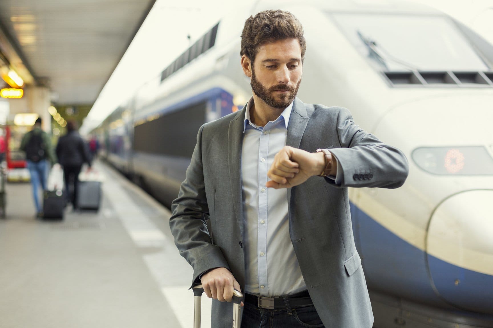 フランスの電車の横に立つ時計を持った男性。