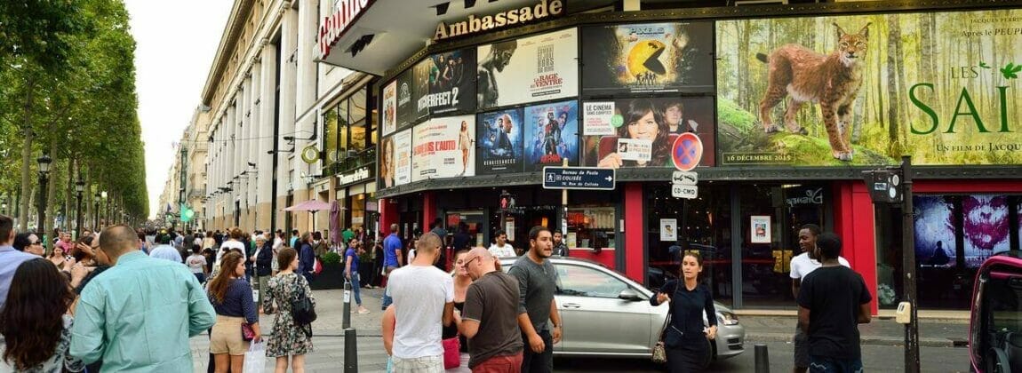 フランスのシャンゼリゼ通りの店の前に立つ大勢の人々。