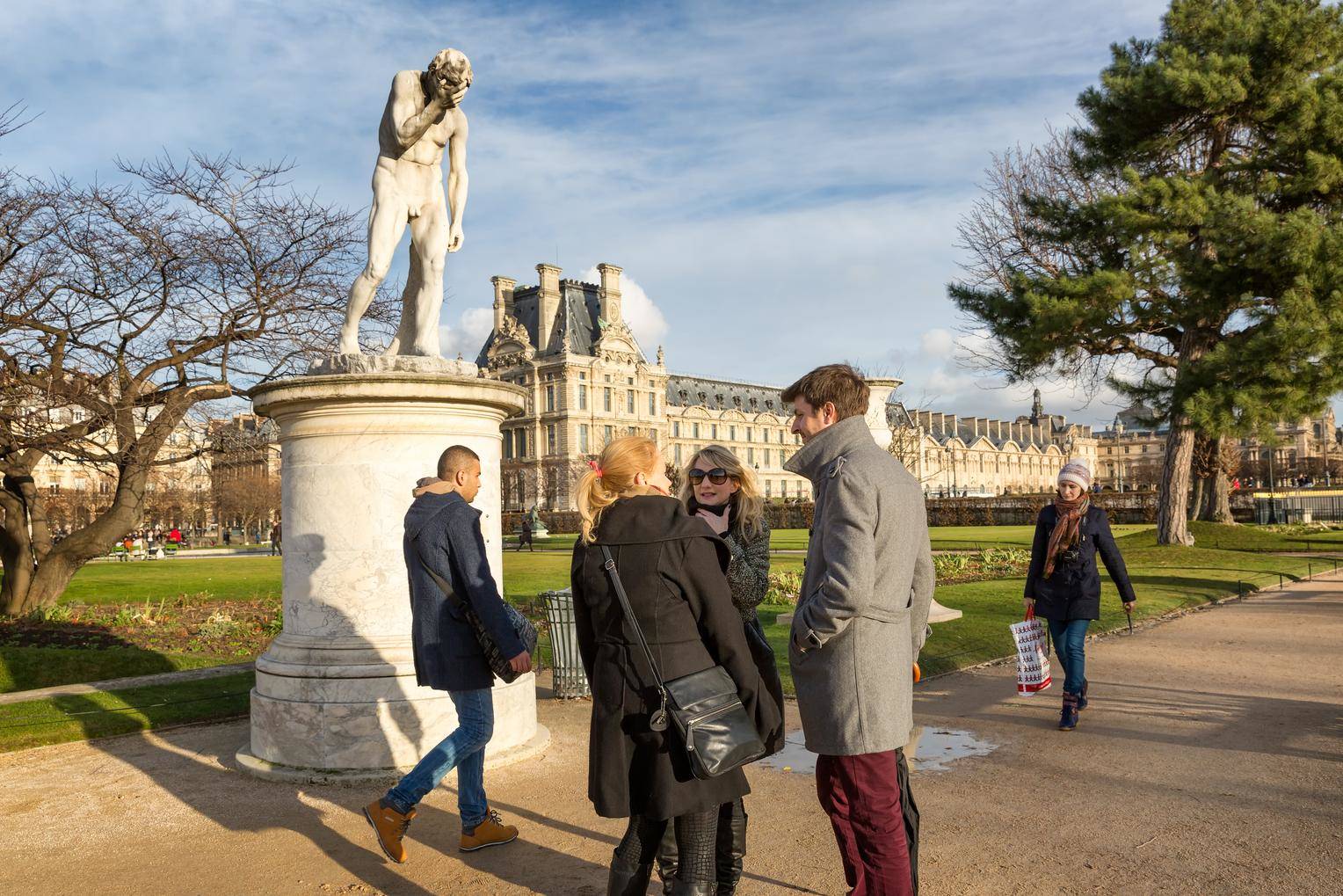 公園の銅像の近くに立つフランス人のグループ。