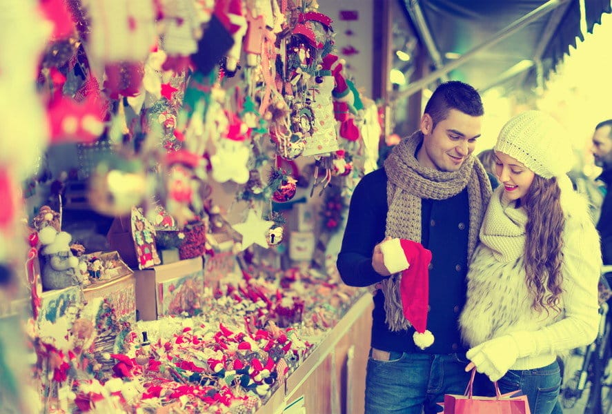 フランスの市場でクリスマスの飾り付けを眺めるカップル。