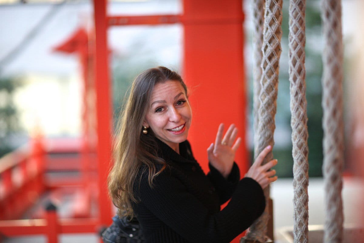 フランスの赤い鳥居の横に立つ黒いジャケットを着た女性。 フランスの赤い鳥居の横に立つ黒いジャケットを着た女性。