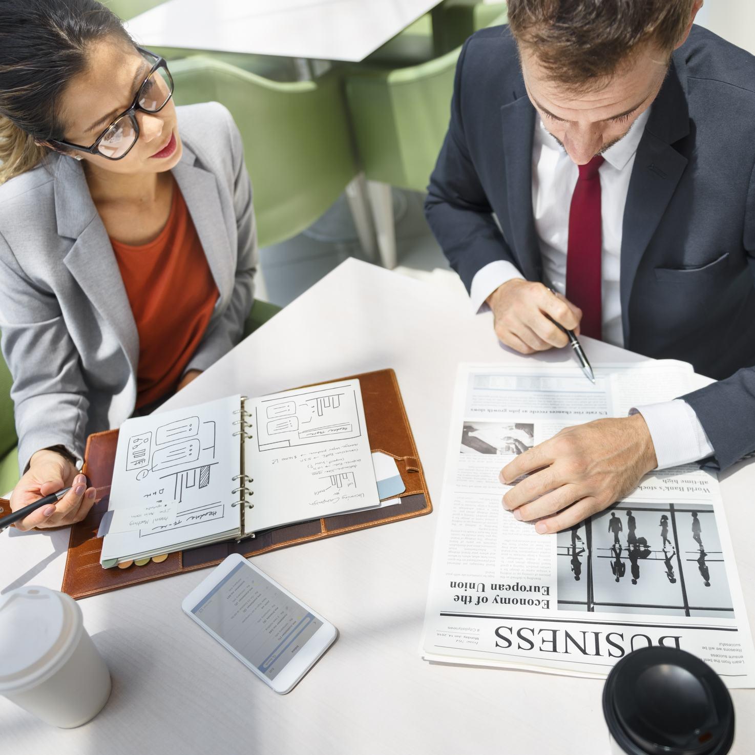 フランスから来た 2 人のビジネスマンがテーブルに座ってノートに書いています。