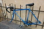 フランスで青い自転車が金属フェンスに立てかけられている。