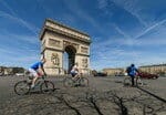 フランスの凱旋門の前で自転車に乗る人々のグループ。