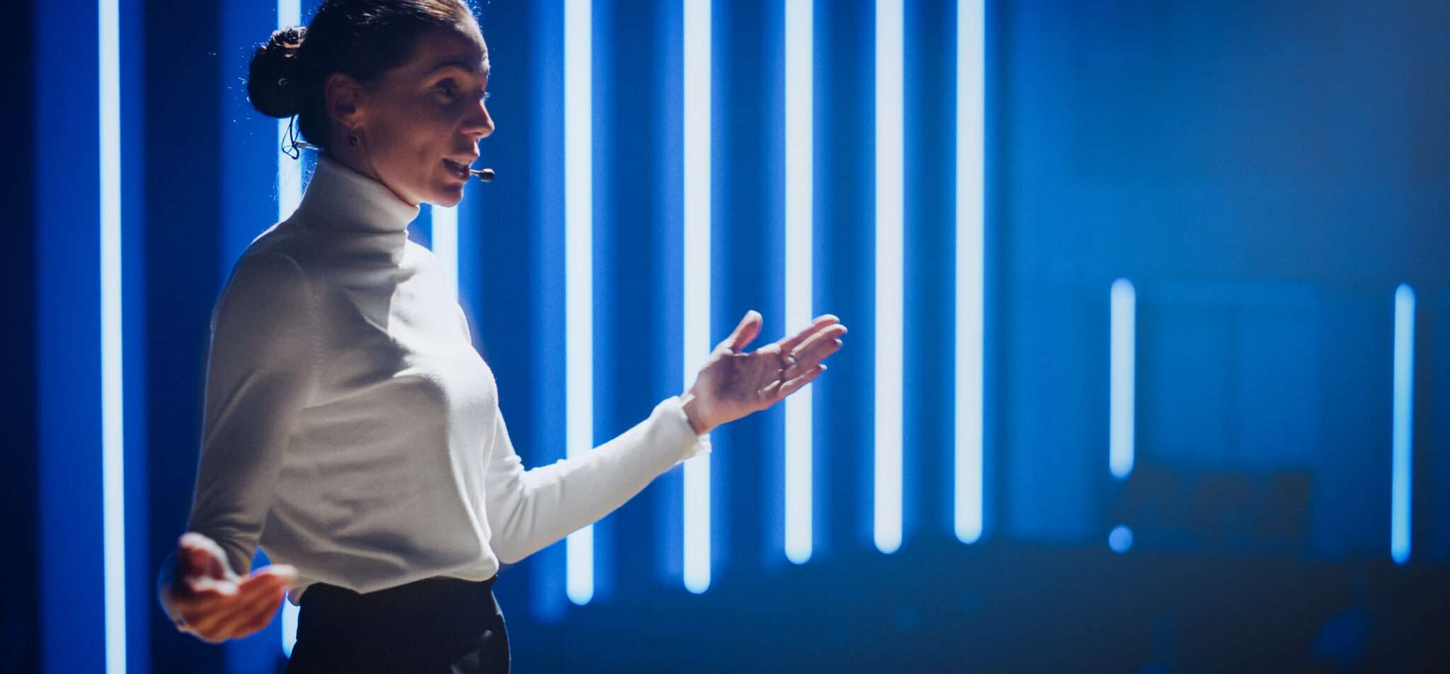 フランスで青いライトの前でプレゼンテーションをする女性。